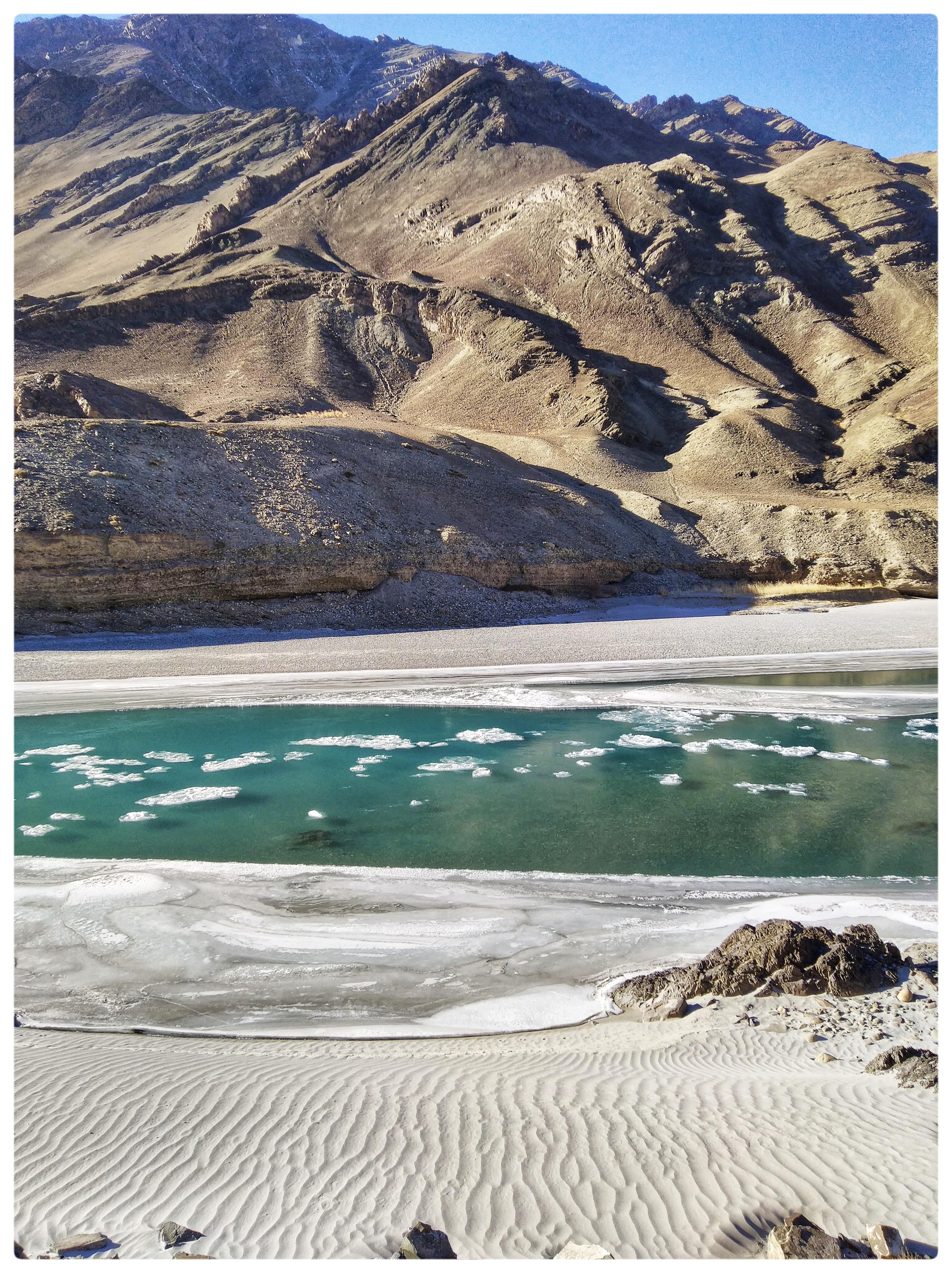  A turquoise Zanskar river bearing sheets of ice flows between windy drawn sand and rocky mountains near Chilling, Ladakh (Source - Artist)